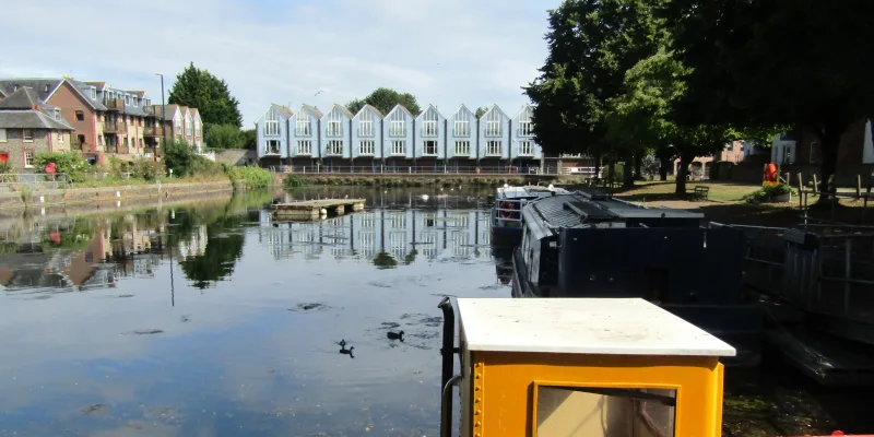 Chichester Canal basin with moored narrowboats and waterside houses