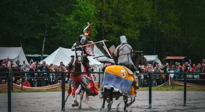 Two armoured riders jousting on horseback in an outdoor arena