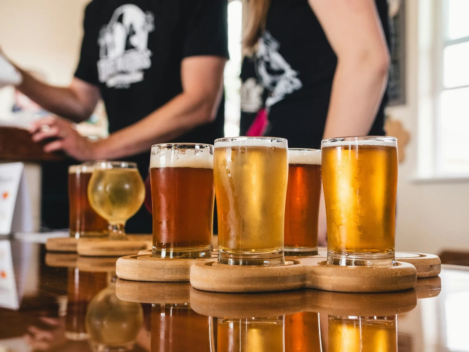 A flight of craft beers on a taproom bar, glasses of pale ale and stout in a row